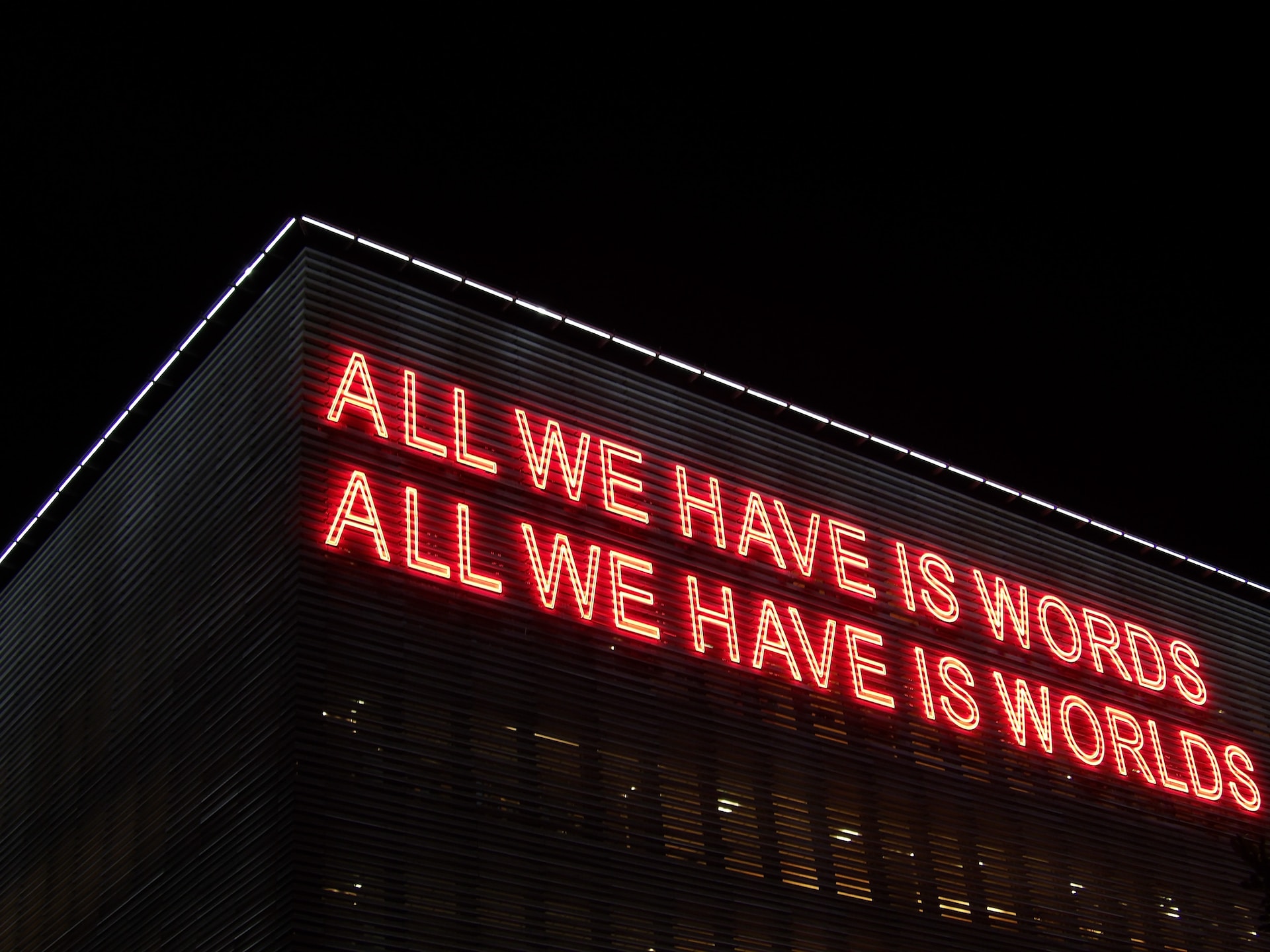 Large Neon Sign on Building says "All We Have is Words" twice